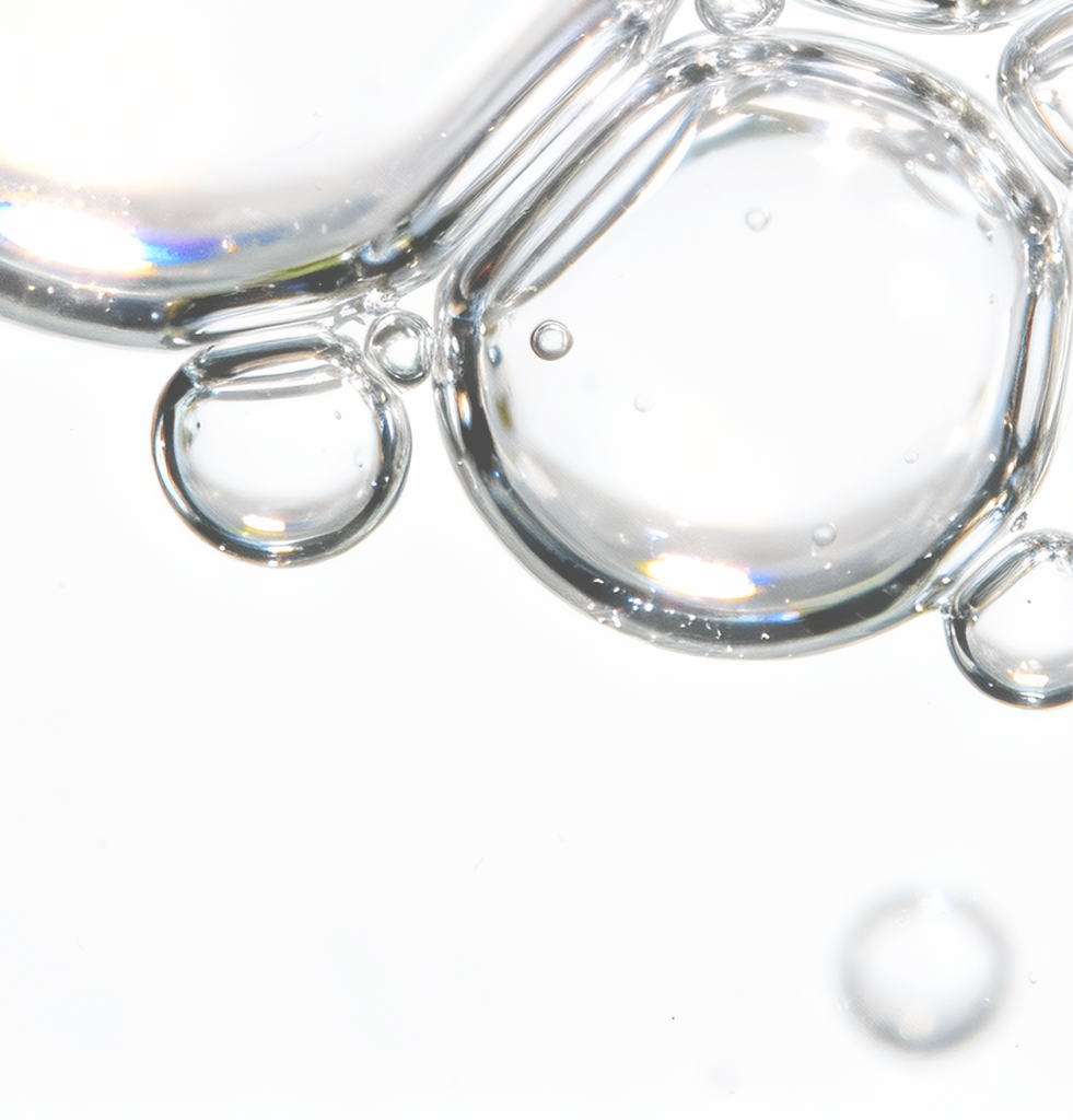 Macro image of clear COSRX serum bubbles illustrating Niacinamide and Adenosine, ingredients known to brighten dull skin, smooth fine lines, and improve elasticity; supports firm, radiant skin as part of a gentle, first-step routine suitable for sensitive skin and slow-aging care.