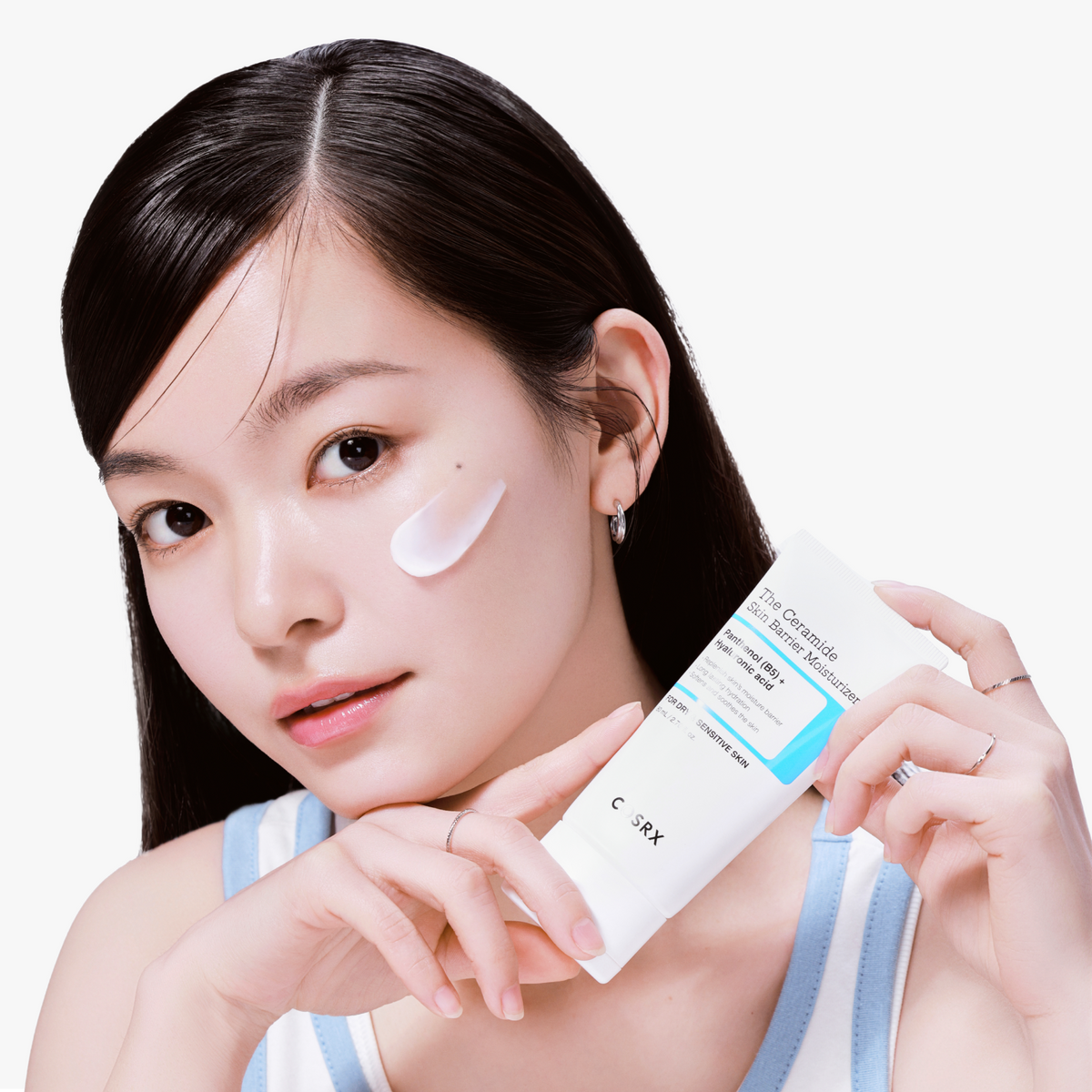 Model holding COSRX The Ceramide Skin Barrier Moisturizer against a light background, showcasing its daily-friendly derma design; a clinically tested Korean moisturizer infused with Ceramides, Cholesterol, Fatty Acids, Panthenol (B5), and 5 types of Hyaluronic Acid that deeply hydrates, strengthens the skin barrier, and delivers a visible soothing effect within 10 seconds, improving comfort by 61.861% and reducing skin temperature by 4.34°C.