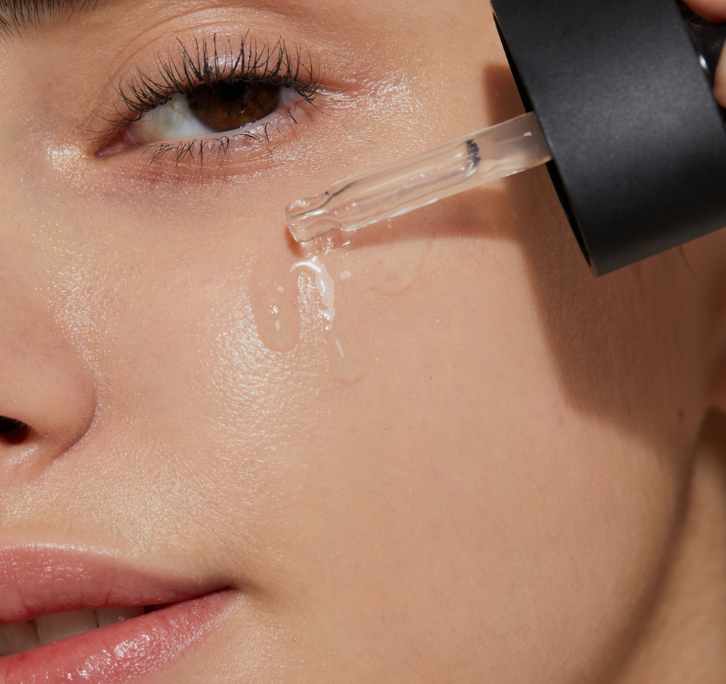 Close-up of COSRX The Niacinamide 15 Serum being applied to cheek with a dropper, showing lightweight formula absorbing smoothly into skin; designed for acne-prone and oily skin to reduce sebum and refine enlarged pores.