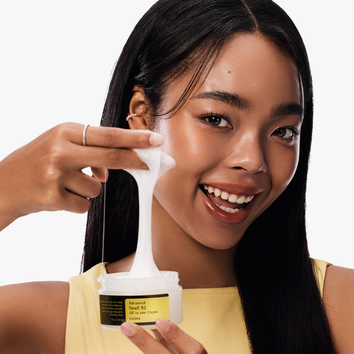 Model holding COSRX Advanced Snail 92 All In One Cream jar, showing hydrated, radiant skin; Korean moisturizer with 92% snail mucin clinically measured to improve hydration by 33.05% using the Epsilon device, supporting barrier repair, elasticity, and visible glow.