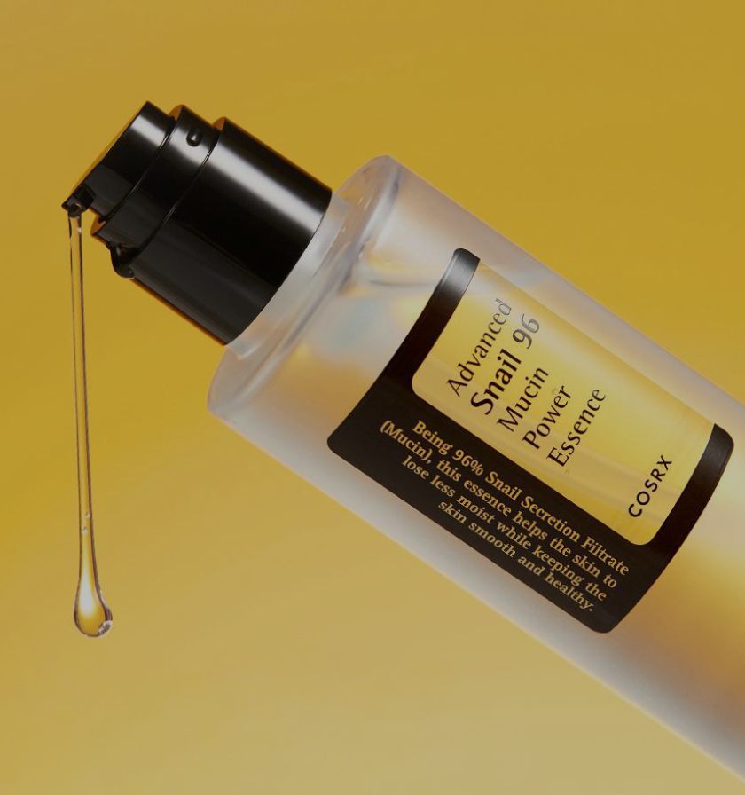 COSRX Advanced Snail 96 Mucin Power Essence shown with drop of serum against golden background; text reading ‘No.1 Global Essence’ highlights its 96% snail secretion filtrate, a glow-boosting Korean skincare formula for instant hydration, radiance, and improved absorption.